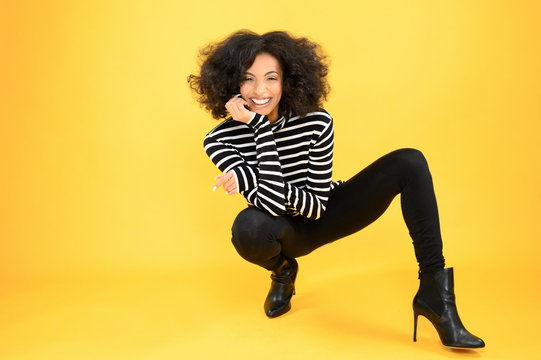 Fun African American Woman Squatting on a Yellow Background