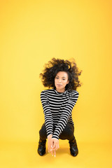 Fun African American Woman Squatting on a Yellow Background