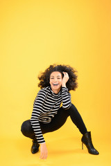 Fun African American Woman Squatting on a Yellow Background