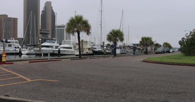 Man woman electric scooter Corpus Christi Texas marina. South Texas tourism travel destination. Waterfront marina, port harbor and scenic byway.  Humid subtropical climate.