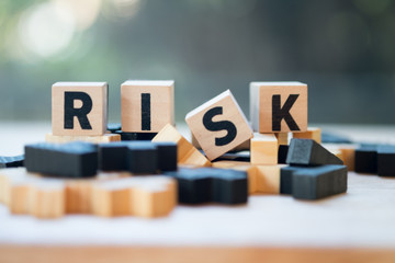 Cube wooden block with alphabet building the word RISK. Risk assessment - obrazy, fototapety, plakaty