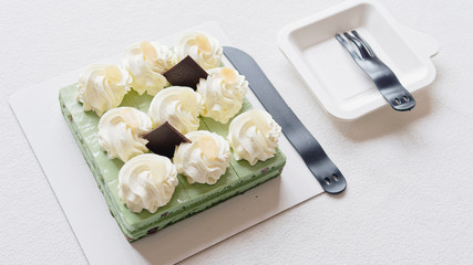 close up of birthday cake, plastic knife and folks on white tablecloth, delicious sweet food and happy birthday concept.