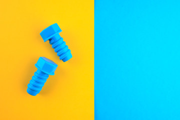 Two toy plastic bolts of blue color on a yellow-blue background.