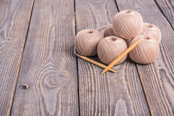 Balls of yarn and knitting needles for knitting on a wooden background.