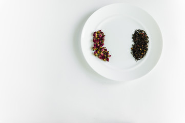 Small buds of red roses and flower tea on a white plate background white