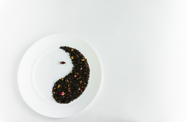 Small buds of red roses and flower tea on a white plate in the form of yin-yang background white
