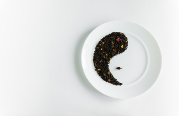 Small buds of red roses and flower tea on a white plate in the form of yin-yang background white