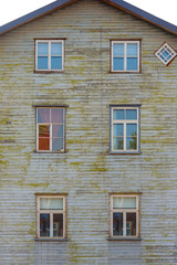 Facade of old brown wooden house with six windows
