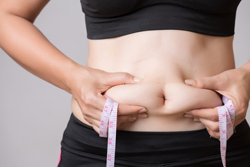 Fat woman hand holding excessive belly fat with measuring tape. Healthcare and woman diet lifestyle...