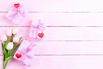 International Womens day concept. Pink tulips and red heart with gift box on white and pink wooden background.