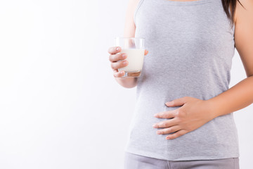 Woman hand holding glass of milk having bad stomach ache because of Lactose intolerance. health problem with dairy food products, Healthcare and medical concept.