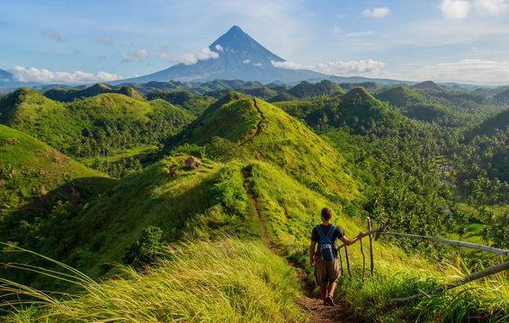 Hiker with backpack looks at the view on the Mayon volcano,Quit in Day Hills area,Philippines
