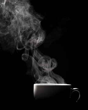 Steaming coffee in cup isolated on black background with copy space.
