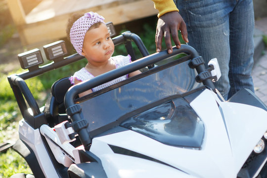 Little Cute Girl Riding A Toy Car In The Summer Park On The Track.