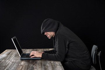 hacker in black hoody with laptop