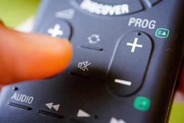 Man holding tv remote commander and press mute button