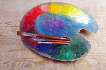 Art palette with artistic paint brushes on a wooden texture
