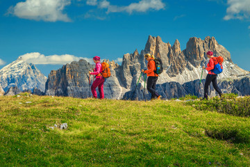 Happy woman hikers with backpacks walking in mountains, Dolomites, Italy