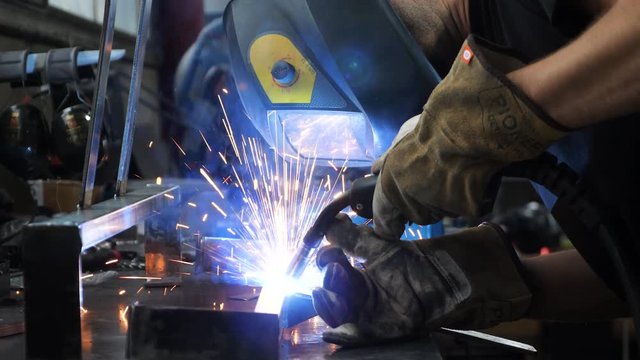 Static shot, of a welder, welding on steel, sparks flyes, when he works precisely and pedantic, at his table, in south Norway