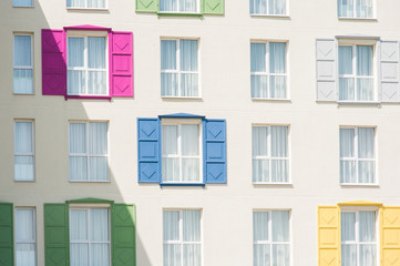 View to facade of building with windows with colored wooden shutters.