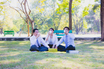 Business team work. They  are talking in the park.  they are talking about business and  on the floor had a notebook and a glass of coffee.Photo concept  business and relax time.