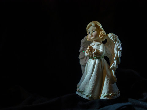 Figure praying angel in the night on a dark background 