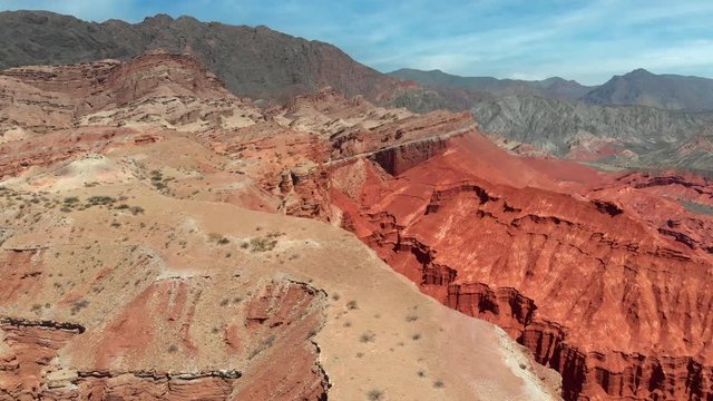Flying over colorful red rocky mountains in Quebrada de Las Flechas valley, Salta, Argentina. Aerial shot, 4K