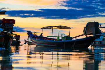 Fototapeta na wymiar Amazing colorful sunset sky with silhouette wooden boat on sea coastline