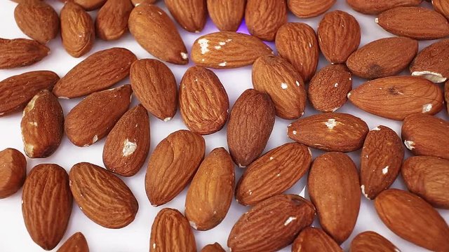 Whole almond almonds nut nuts closeup texture video on rolling rotating looping plate