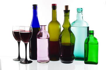 Two glasses of wine and bottles of wine and gin on the light.