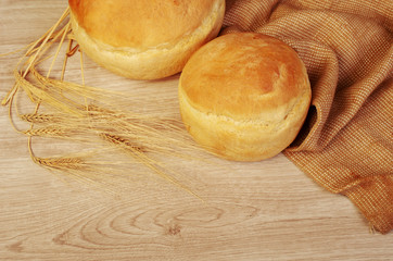 Two loafs of white bread, canvas and ears on a wooden table