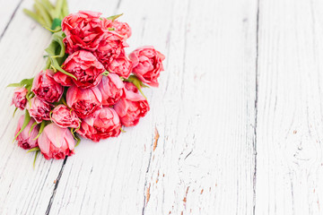 Red tulips bouquet on white wooden background