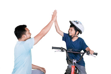 Boy and father making high five on a bicycle