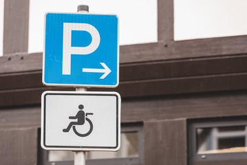 two signs with a P for parking and a symbol of a wheelchair for a disabled parking space
