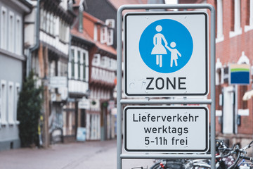 street sign for a pedestrian zone in front of old half-timbered houses and bicycles (Translation:...