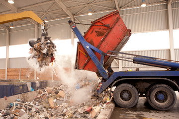 Truck dumps waste to the incinerator, hole where the big grab take the rubbish and put it into fire. All waste is being processed in the incinerator and burning without any air pollution. - obrazy, fototapety, plakaty