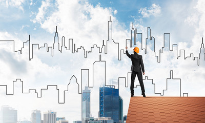 Man architect draw silhouette of modern city on blue sky. Mixed media