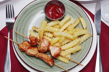 Fried potatoes, meat skewers, ketchup on a plate