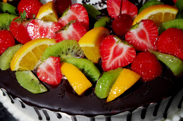 Fruit cake made of chocolate and strawberries, kiwi, oranges, cherries