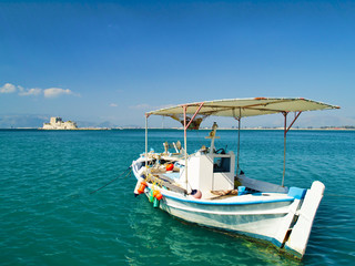 Obraz premium Boat in Nafplio Greece, with mpourtzi castle in background. A bright sunny day.