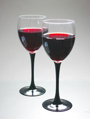 Two glasses of red wine on gray