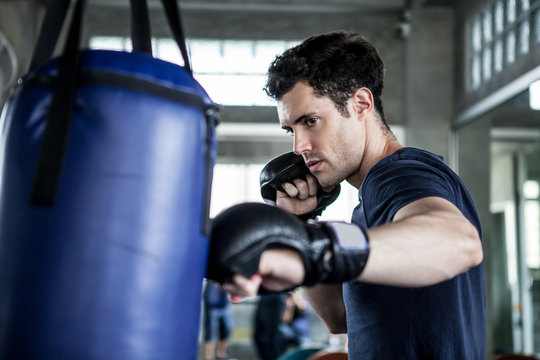 Handsome young man boxer is exercising with a punching bag at training fitness gym.male boxing workout sport