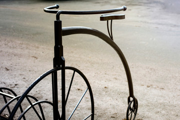 An old retro metal bike with a large front wheel and a small rear wheel also serves to park bikes.