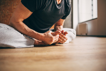 Young man doing yoga in big bright training gym