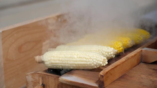 Close up of appetizing grilled sweet corn on the bbq grill. Street food festival in japan. Slow motion-the smoke from cooking movement