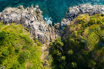 View from above, stunning aerial view of a beautiful tropical rocky coast with palm trees bathed by a turquoise and clear water, Freedom Beach, Phuket, Thailand.