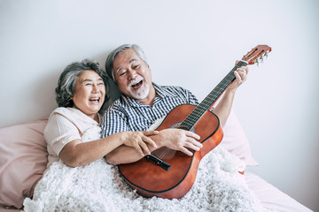 Senior couple  relax playing acoustic guitar in bed room