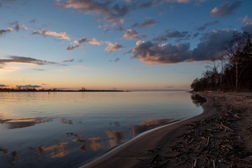calm lake in bright sun light with reflections of clouds and trees and blue sky