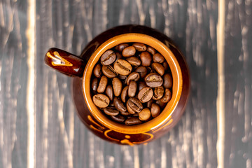 Coffee cup with roasted beans on black wooden background. Top view with copy space and soft focus.