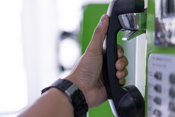 Hands that are holding a public phone to call emergency.